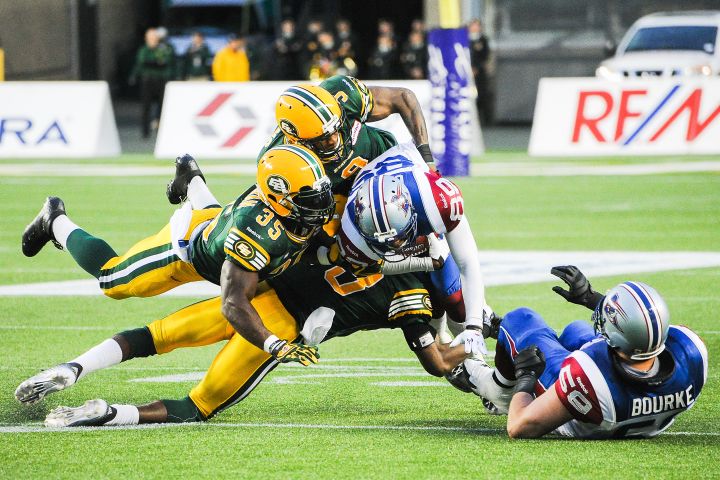 Rennie Curran #35 (L) and Patrick Watkins #9 (top) of the Edmonton Eskimos jump on top of Duron Carter #89 of the Montreal Alouettes during a CFL game at Commonwealth Stadium on September 12, 2014 in Edmonton, Alberta, Canada.