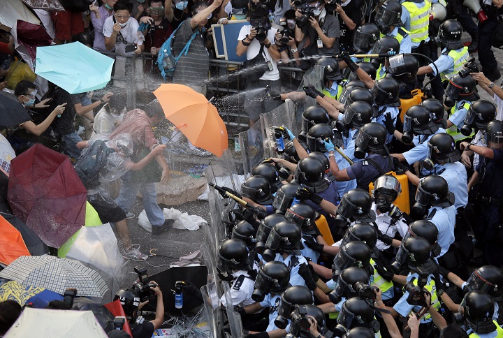 Riot police use pepper spray against protesters after thousands of people block a main road to the financial central district outside the government headquarters in Hong Kong, Sunday, Sept. 28, 2014.