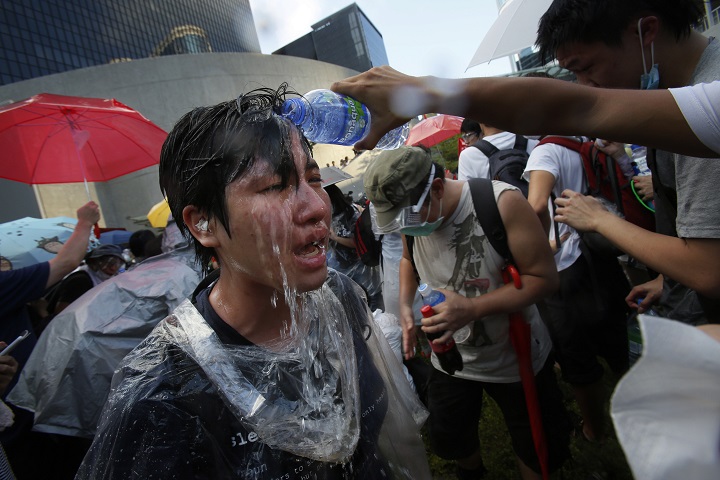 A student protester is overcome by pepper spray from riot police as thousands of protesters surround the government headquarters in Hong Kong Sunday, Sept. 28, 2014.