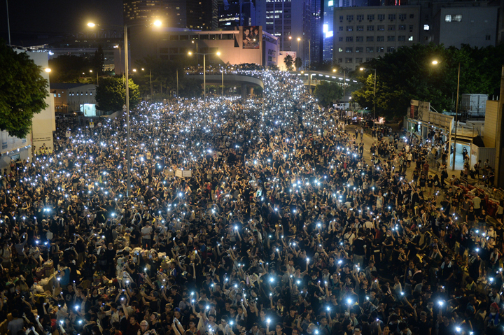 Pro-democracy demonstrators hold up their mobile phones during a protest near the Hong Kong government headquarters on September 29, 2014.