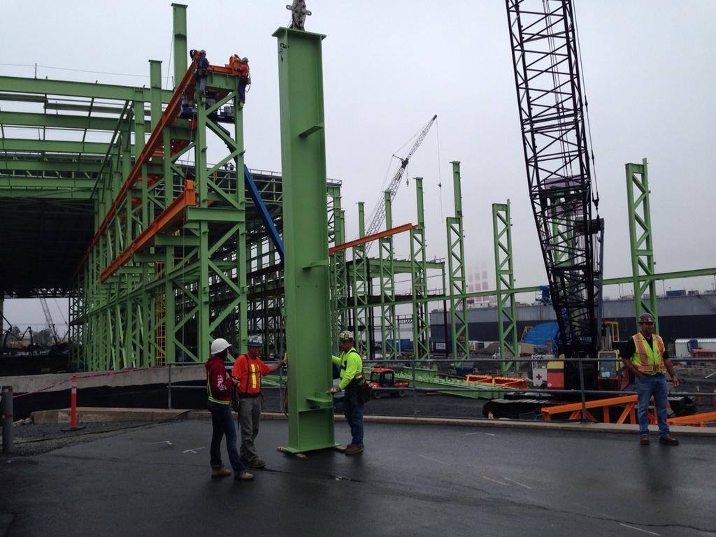 Workers stand near a steel beam to be installed at the Irving Shipyard in Halifax on Sept. 3, 2014.