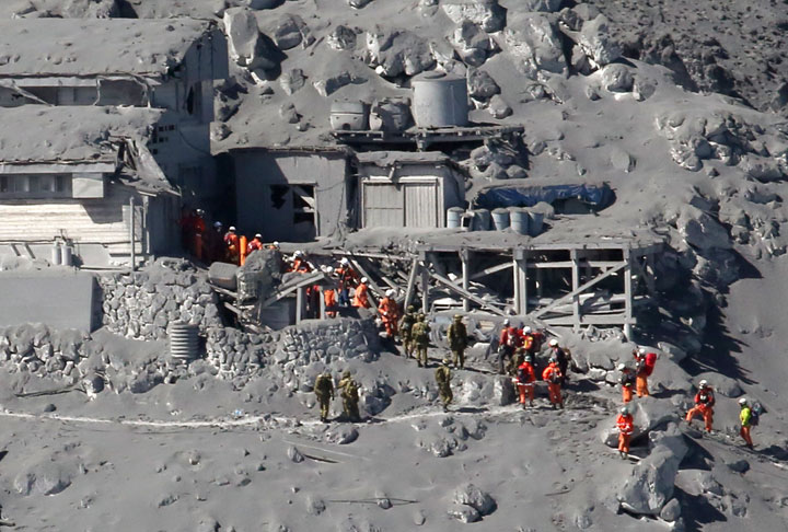 This aerial picture taken on September 28, 2014 shows rescue workers and Self Defence Force soldiers searching for missing climbers and survivors among ash covered mountain cottages on the top of Mount Ontake at Nagano prefecture, one day after Japan’s volcano Ontake erupted in central Japan, which straddling Nagano and Gifu prefecture.
