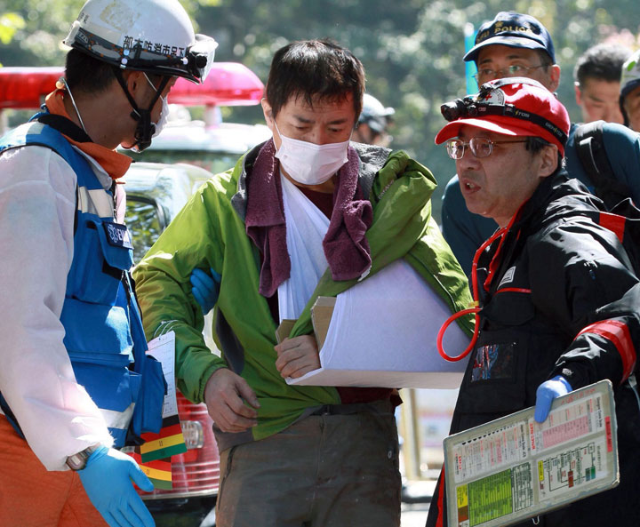 An injured climber, center, is helped by a firefighter, left, after descending Mount Ontake in Gero, Gifu prefecture, central Japan Sunday, Sept. 28, 2014.