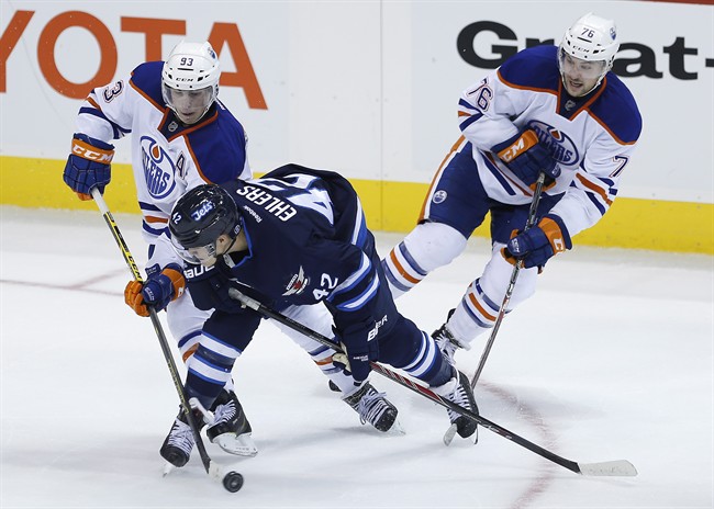 Edmonton Oilers forward Ryan Nugent-Hopkins (93) and Travis Ewanyk (76) battle for the puck with Winnipeg Jets forward Nikolaj Ehlers (42) during third period NHL pre-season action in Winnipeg on Wednesday, September 24, 2014.