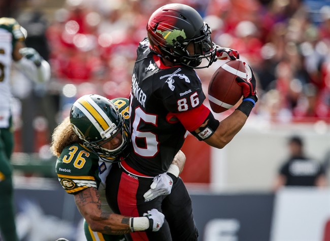 Edmonton Eskimos' Aaron Grymes, left, tries to stop Calgary Stampeders' Anthony Parker, from scoring a touchdown during first half CFL football action in Calgary, Alta., Monday, Sept. 1, 2014. 