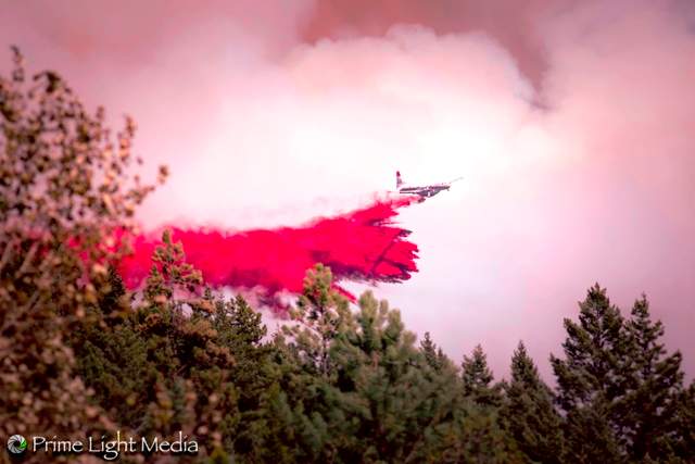 A firefighting aircraft dumps fire retardant on an area near the community of Joe Rich.