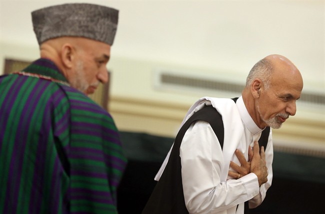 Afghanistan's presidential election candidate Ashraf Ghani Ahmadzai, right, leaves after signing a power-sharing deal as president Hamid Karzai, left, stands at the presidential palace in Kabul, Afghanistan, Sunday, Sept. 21, 2014. THE CANADIAN PRESS/AP, Massoud Hossaini.