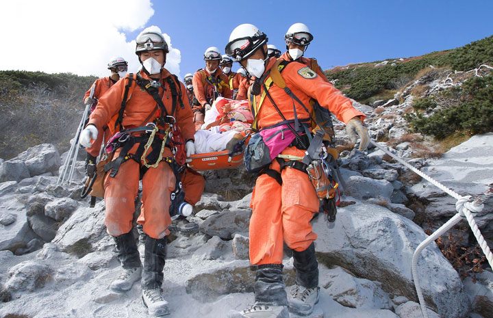 In this Sunday, Sept. 28, 2014 photo released by Tokyo Fire Department, firefighters carry a hiker trapped in the summit area of Mount Ontake during Saturday's initial eruption during rescue operations in central Japan.