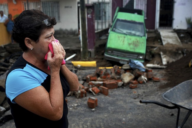 Maria del Carmen Gonzalez watches after part of a street and her home collapsed due to heavy rains in the Gulf port city of Veracruz, Mexico, Tuesday Sept. 2, 2014. 