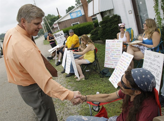 In this Sunday, Aug. 22, 2010 photo, Pastor Bill Dunfee, left, of New Beginnings Ministries Church, greets supporters of The Fox Hole strip club as they protest against his church in Warsaw, Ohio. 