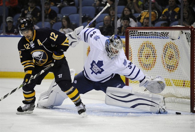 Buffalo Sabres right winger Brian Gionta (12) deflects the puck on goal as Toronto Maple Leafs goaltender James Reimer (34) defends during the first period of an NHL hockey preseason game, Friday, Sept. 26, 2014, in Buffalo, N.Y. 