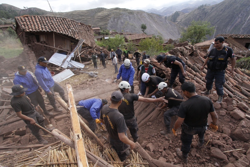 Rescue workers search for bodies in the ruins of a collapsed house after a 4.9 magnitude earthquake shook the remote Andean village of Paruro near the city of Cuzco, Peru, Sunday Sept 28, 2014. The moderate quake centered just 5 miles underground killed at least 8 people destroying homes that left dozens homeless as well as knocking out power in the village. 