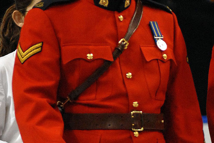 File: A pair of RCMP officers, one male and one female, in their Mountie red serge dress uniforms take part in a medal ceremony.