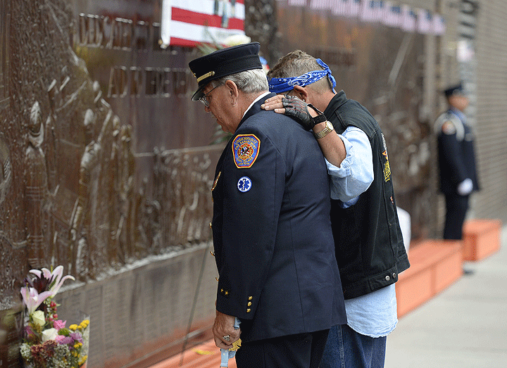 Firefighters pay their respects at the at the Fire Department of New York (FDNY) Memorial Wall Located at FDNY Engine 10 and Ladder September 11, 2014.