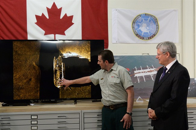 Prime Minister Stephen Harper listens to details from Parks Canada's Ryan Harris about the find from the Victoria Strait Expedition in Ottawa on Tuesday September 9, 2014.