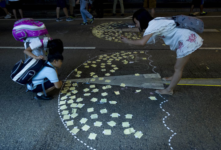 A woman takes a picture of her children in front of an umbrella drawn on the floor in the Mong Kok district of Hong Kong on September 30, 2014.