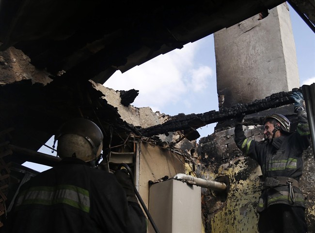 Firefighters try to extinguish a fire at a damaged house after shelling in the town of Donetsk, eastern Ukraine, Friday, Sept. 26, 2014.