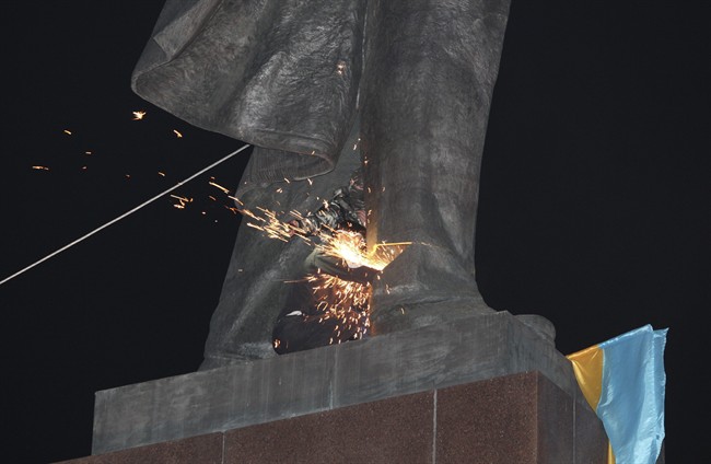 An activist dismantles Ukraine's biggest monument to Lenin at a pro-Ukrainian rally in the central square of the eastern city of Kharkiv, Ukraine, Sunday, Sept.28, 2014.