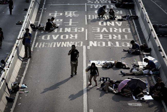 Student activists sleep, sit and walk on a road near the government headquarters where pro-democracy activists have gathered and made camp, Tuesday, Sept. 30, 2014, in Hong Kong.