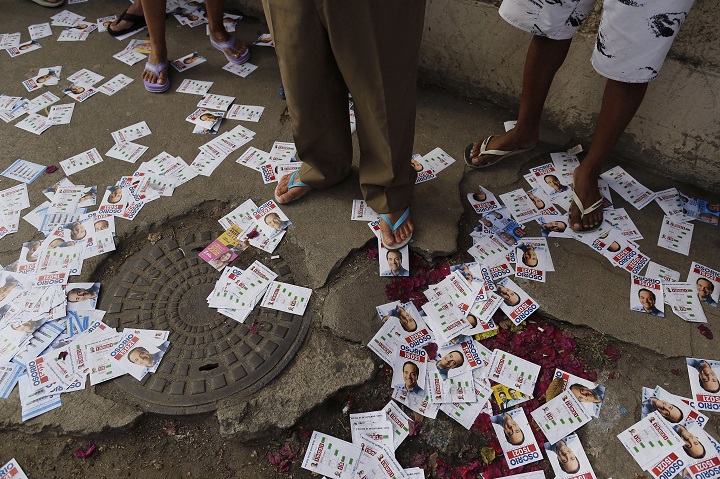 Campaign propaganda litters the sidewalk where people wait in line to vote in general elections outside a school in the Nova Holanda slum, inside the complexo da Mare in Rio de Janeiro, Brazil, Sunday, Oct. 5, 2014. 