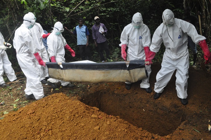A burial team in protective gear bury the body of woman suspected to have died from Ebola virus in Monrovia, Liberia. Saturday, Oct, 18, 2014. 