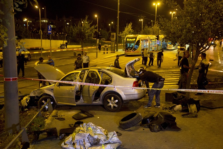 Israeli police officers inspect a car at the scene of an attack in Jerusalem, Wednesday, Oct. 22, 2014.