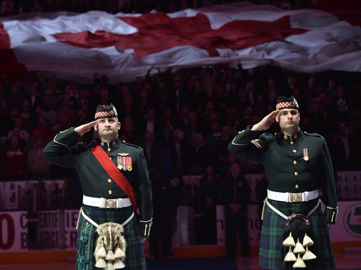 Members of the Canadian Forces salute as they take part in a pre-game ceremony honoring the two fallen soldiers in the recent attacks on Canadian soil before NHL hockey action between the Toronto Maple Leafs and the Boston Bruins.