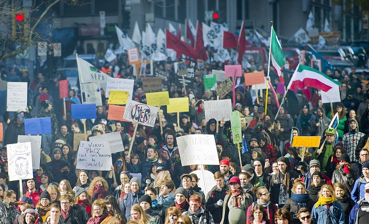 Protesters hold up signs during an anti-austerity demonstration in Montreal Friday, October 31, 2014.