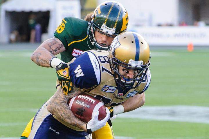 Aaron Grymes #36 of the Edmonton Eskimos tries to tackle Rory Kohlert #87 of the Winnipeg Blue Bombers during a CFL game at Commonwealth Stadium on Thanksgiving Day in Edmonton. The Eskimos defeated the Blue Bombers 41-9.
