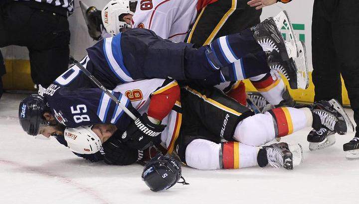 Mathieu Perreault (85) of the Winnipeg Jets hangs on to Dennis Wideman (6) of the Calgary Flames after players got into a shoving match at the MTS Centre Sunday.