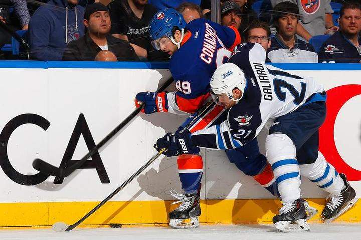Cory Conacher of the New York Islanders and T.J. Galiardi of the Winnipeg Jets battle for the puck along the boards at Nassau Veterans Memorial Coliseum in New York.