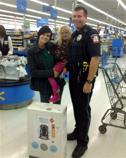 This photo provided by Walmart shows Emmett Township, Mich., Department of Public Safety Officer Ben Hall, right, with Alexis DeLorenzo, her daughter and the child's seat he purchased for them. 