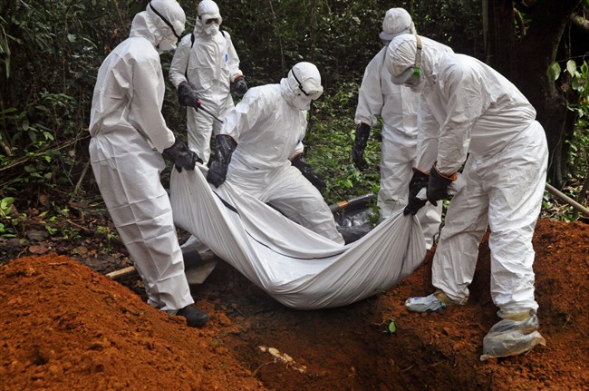 Health workers bury the body of a woman who is suspected of having died of the Ebola virus in Bomi county, on the outskirts of Monrovia, Liberia, Monday, Oct. 20, 2014.