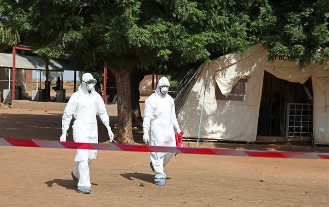 In this photo taken Saturday, Oct. 25, 2014, health workers walk towards an area used for Ebola quarantine after they worked with diseased Fanta Kone at a Ebola virus center in Kayes, Mali.