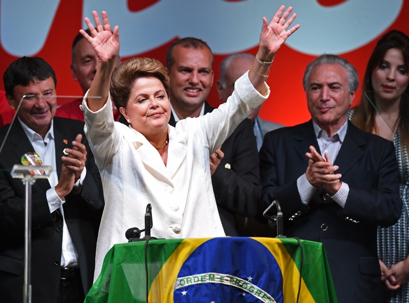 Re-elected Brazilian President Dilma Rousseff (C) waves next to her Vice-President Michel Temer (R) following her win, in Brasilia on October 26, 2014. Leftist incumbent Dilma Rousseff was re-elected president of Brazil, the country's Supreme Electoral Tribunal said, after a down-to-the-wire race against center-right challenger Aecio Neves. Rousseff, who had 51.45 percent of the vote with 98 percent of ballots counted, was declared the run-off winner. 