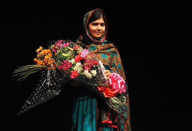 Malala Yousafzai poses with a bouquet after speaking during a media conference at the Library of Birmingham, in Birmingham, England, Friday, Oct. 10, 2014, after she was named as winner of The Nobel Peace Prize.