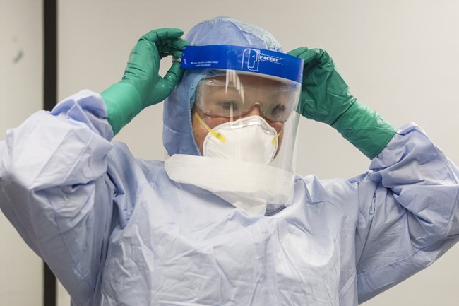 A healthcare professional adjusts her mask during a demonstration of Personal Protective Equipment (PPE) procedures at Toronto Western Hospital on Friday October 17, 2014.