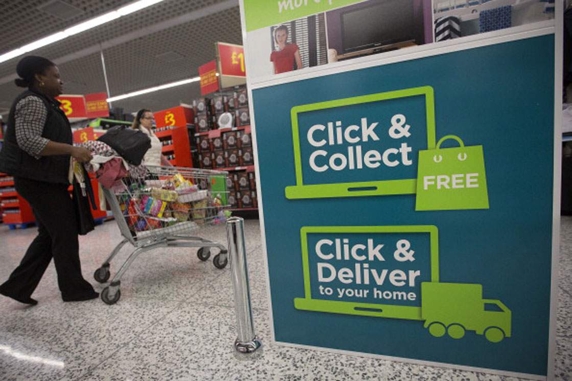 A customer pushes a shopping cart past a 'click and collect' pick-up point inside a Walmart-owned store in the United Kingdom. Some grocers have begun trialing the same service in Canada.