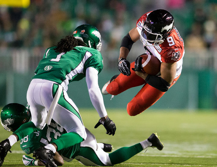 Jon Cornish #9 of the Calgary Stampeders is sent airborne by Tristan Jackson #38 of the Saskatchewan Roughriders in a game between the Calgary Stampeders and Saskatchewan Roughriders in week 15 of the 2014 CFL season at Mosaic Stadium on October 3, 2014 in Regina.