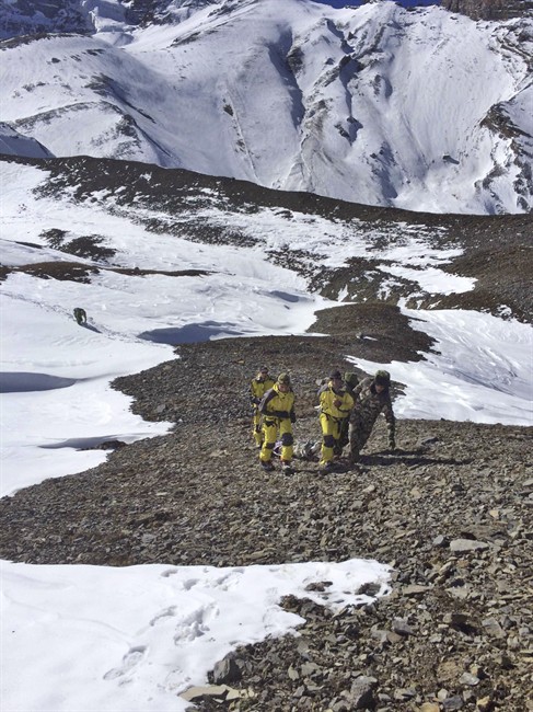 In this photo provided by the Nepalese Army, rescue team members carry a victim of an avalanche before they airlift the body from Thorong La pass area in Nepal, Thursday, Oct. 16, 2014.