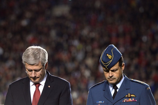 Prime Minister Stephen Harper, left, and General Thomas Lawson, Chief of the Defence Staff, participate in a tribute to the Canadian Forces, as well as fallen heroes, Corporal Nathan Cirillo and Warrant Officer Patrice Vincent, before the start of CFL action between the Ottawa Redblacks and the Montreal Alouettes in Ottawa on Friday Oct. 24, 2014. 