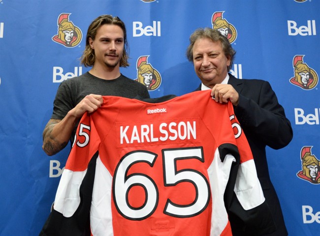 Erik Karlsson, left, and Eugene Melnyk, owner of the Ottawa Senators Hockey Club, hold Karlsson's jersey at a news conference Thursday, Oct.2, 2014 in Ottawa.