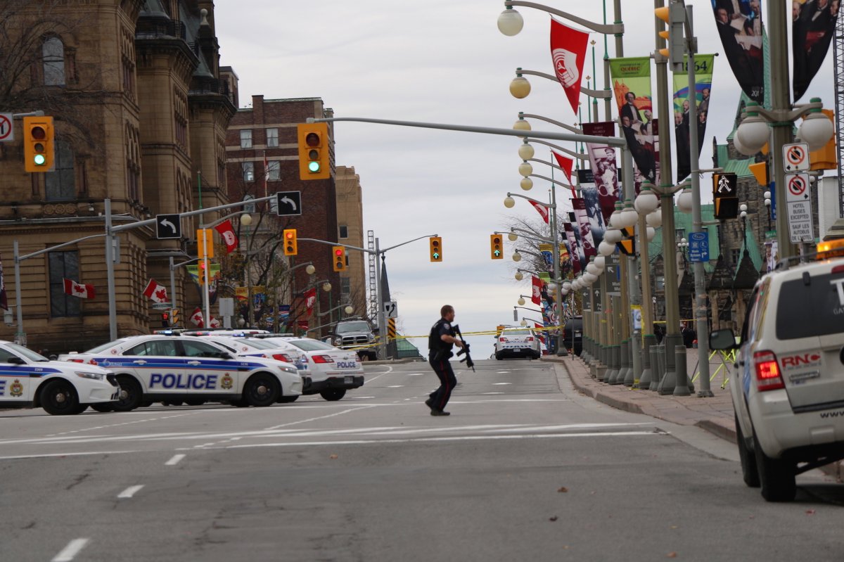 An armed officer dashes across Wellington in downtown Ottawa Wednesday, Oct. 22.
