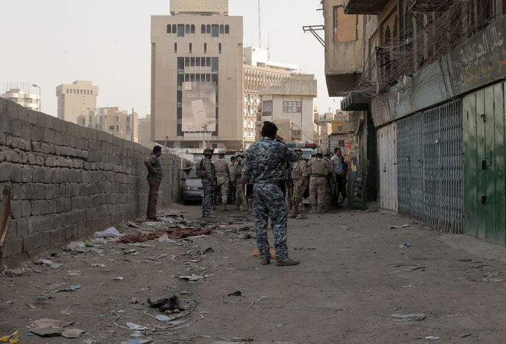 Iraqi security forces gather in front of al-Khairat Mosque after a suicide bomber blew himself up among Shiite worshippers after midday prayers as they were leaving the mosque, killing and wounding tens of people in a commercial area in the city center of Baghdad, Iraq, Monday, Oct. 20, 2014.