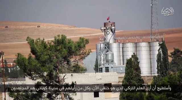 British ISIS hostage John Cantlie, in a propaganda video posted online Oct. 27. In the distance behind Cantlie, wheat silos with a Turkish flag on top can been seen, suggesting the video was taken near the border with Turkey.