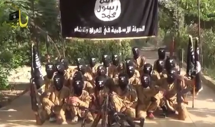 Children pose with guns in front of ISIS flags at a purported training camp near Damascus, Syria. The image comes from a propaganda video released by ISIS.