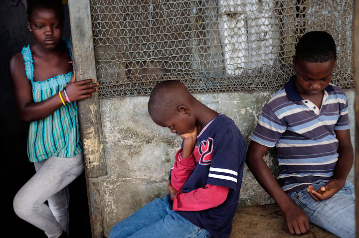 In this photo taken Sunday, Sept. 28, 2014, Promise Cooper, 16, Emmanuel Junior Cooper, 11, and Benson Cooper, 15, sit at their St. Paul Bridge home in Monrovia, Liberia. The Cooper children are now orphans, having lost their mother Princess in July, and their father Emmanuel in August. Their 5-month-old baby brother Success also succumbed to the virus in August. Ruth, their 13-year-old sister is being hospitalized with Ebola. The three never fell sick to the deadly disease.