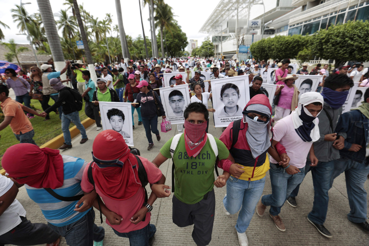 Masked demonstrators march with photographs of missing students and chant slogans to protest the disappearance of 43 students from the Isidro Burgos rural teachers college in Acapulco, Guerrero state, Mexico, Friday, Oct. 17, 2014. 