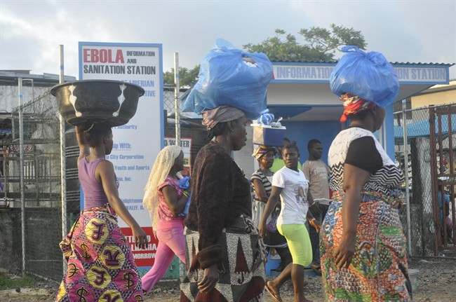 Women walk past a sign warning people of the deadly Ebola virus in Monrovia, Liberia, Friday, Oct. 10, 2014.