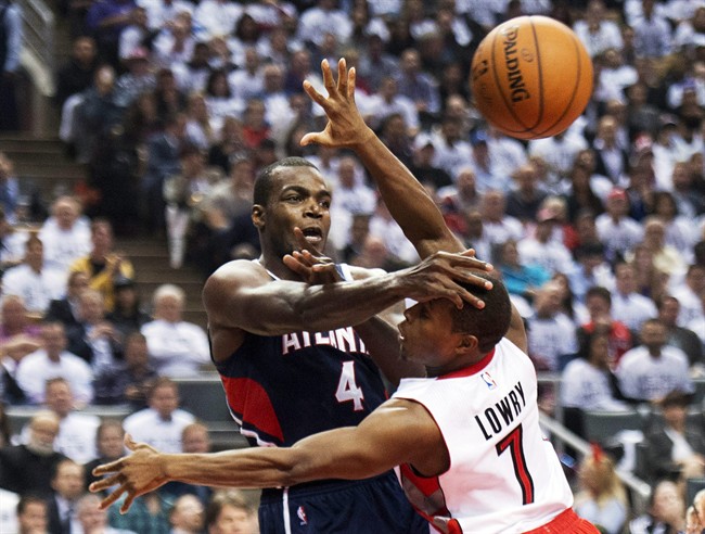 Toronto Raptors guard Kyle Lowry, right, battles for the ball against Atlanta Hawks forward Paul Millsap, left, during the first half of an NBA basketball game in Toronto on Wednesday, Oct. 29, 2014. 